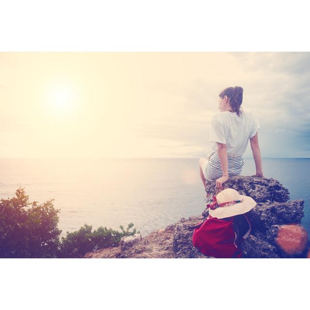 Young Woman With Hat And Backpack Sitting On A Cliff by Littlehenrabi - Wrapped Canvas Print Ebern Designs Size: 81cm H x 122cm W on Productcaster.